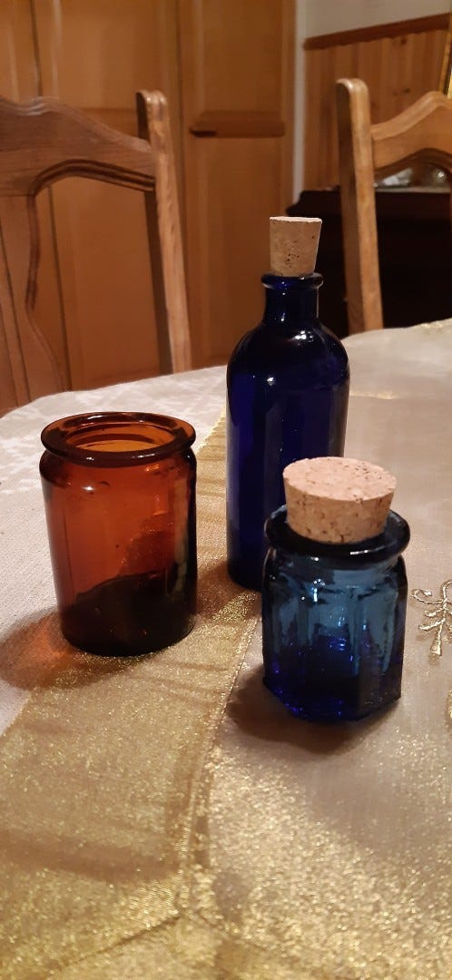 Pieni, vanha, sininen lasipullo ja vanhat purkit