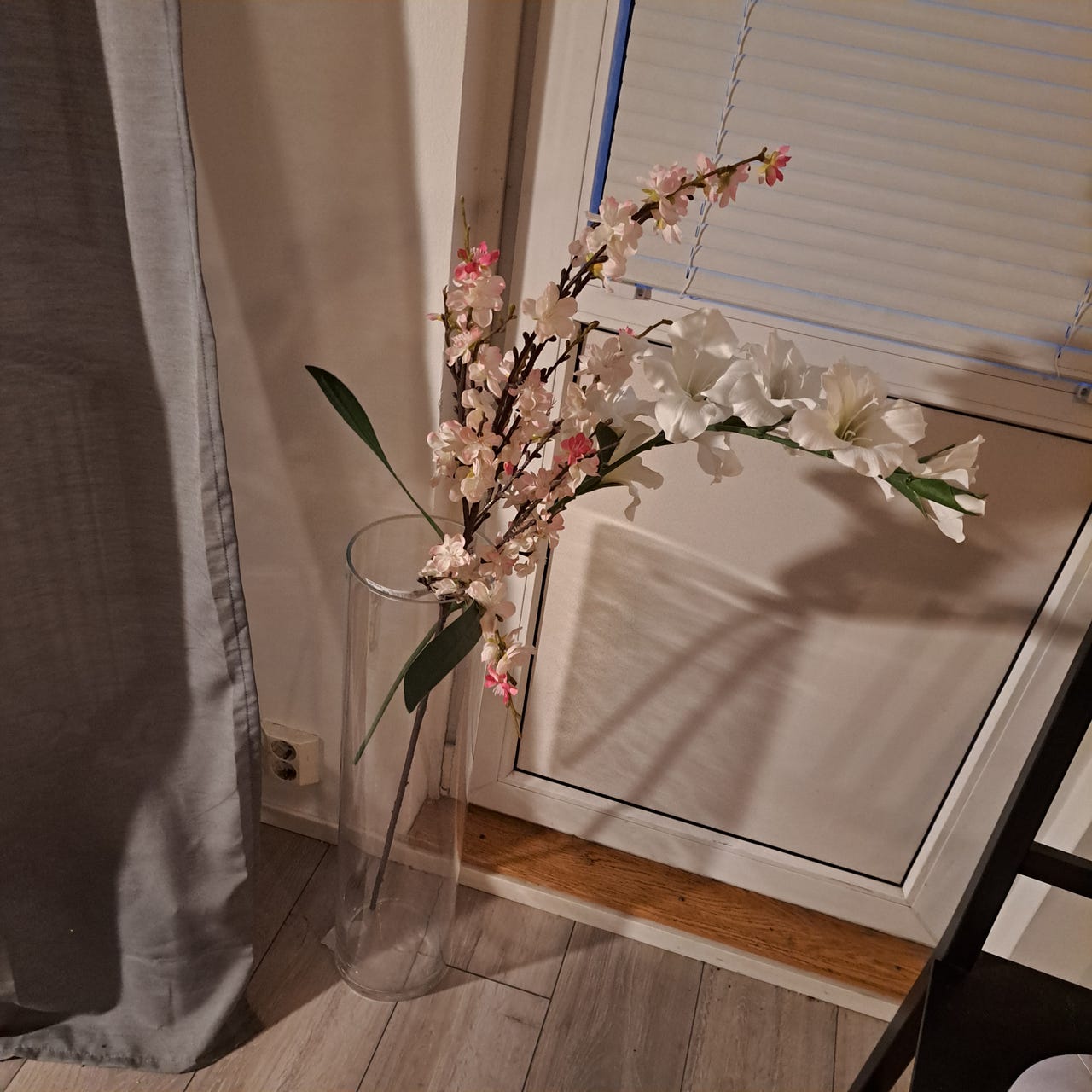 Korkea lasimaljakko ja tekokukat