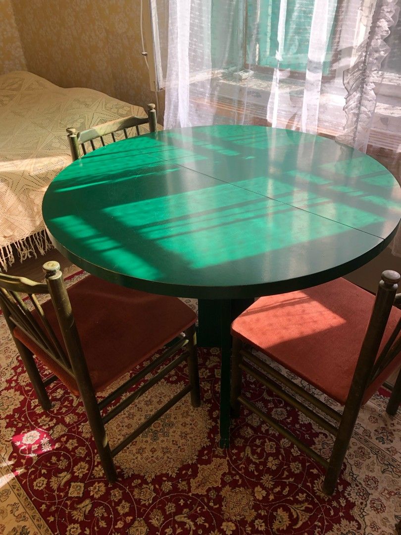 Pyöreä vihreä pöytä ja neljä tuolia