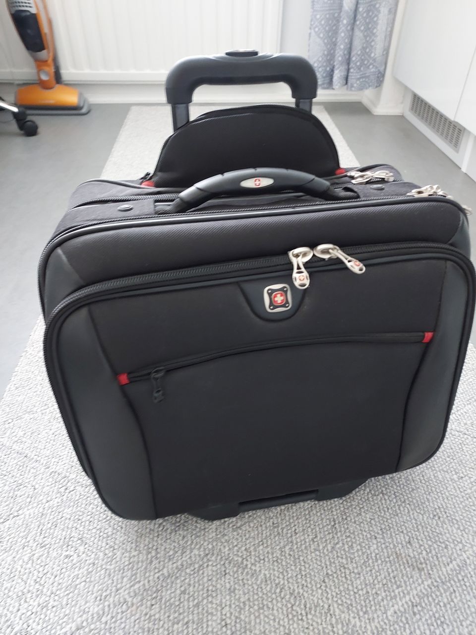 Käyttämätön matkalaukku vetokahvalla, jonka päälle voi laittaa toisen laukun.