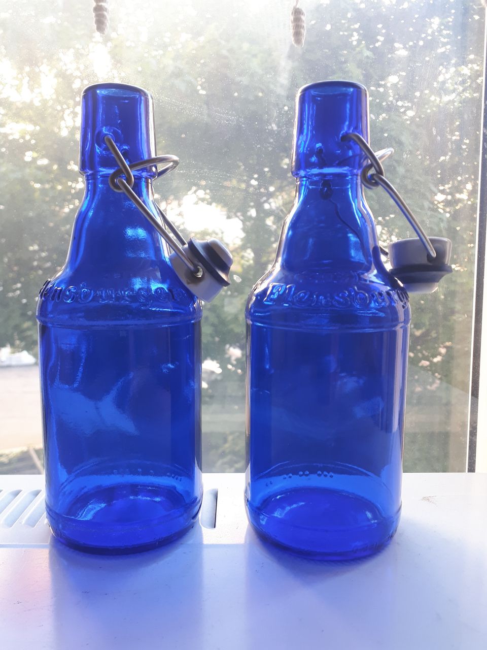 Kaksi tumman sinistä lasipulloa posliinikorkeilla
