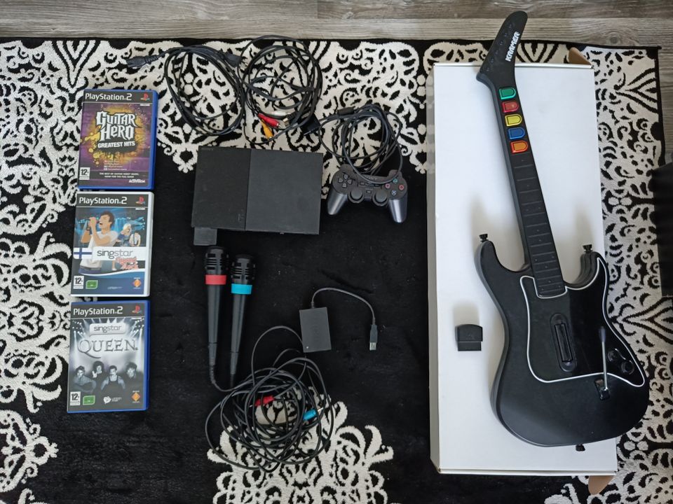 Playstation 2 -konsoli, Guitar Hero -kitara, SingStar-mikit ja muutama peli