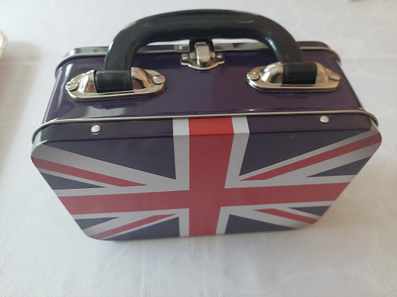 Pieni peltinen laatikko kantokahvalla. Union Jack -lippu etu ja takakannessa.