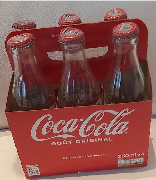 Kuusi lasista Coca-Cola pulloa kantotelineessä