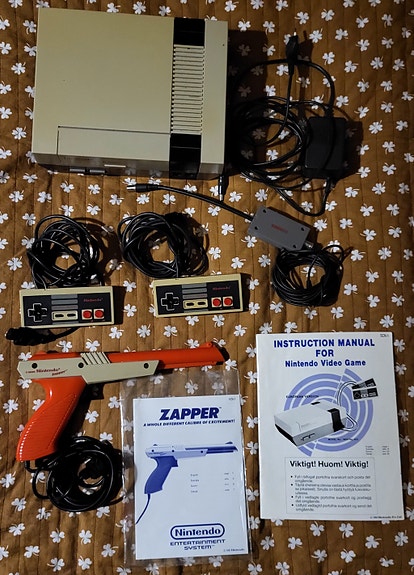 NES konsoli + 7 peliä + Zapper + Game Genie + koodivihko