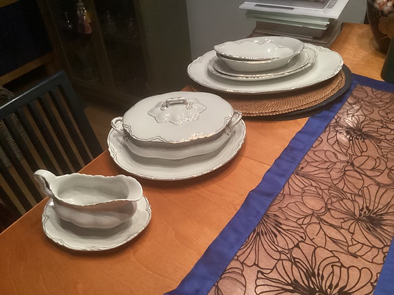 Valkoinen posliininen astiasto koristeellisella reunalla