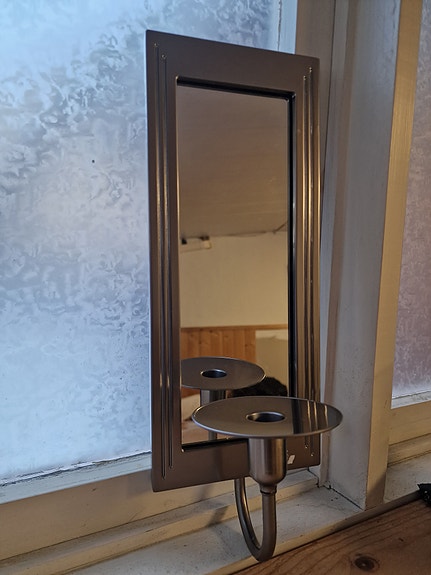 Peili mustalla kehyksellä ja kynttilänjalat