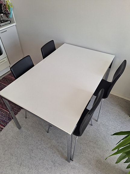 Valkoinen ruokapöytä ja mustat tuolit