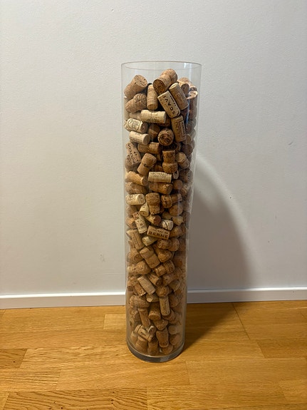 Korkea lasimaljakko täynnä pullonkorkkeja