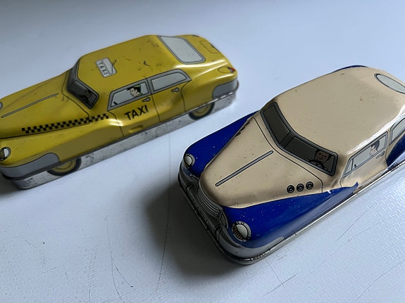 Peltiset autokoriste-rasiat, keltainen taksi ja sinivalkoinen auto