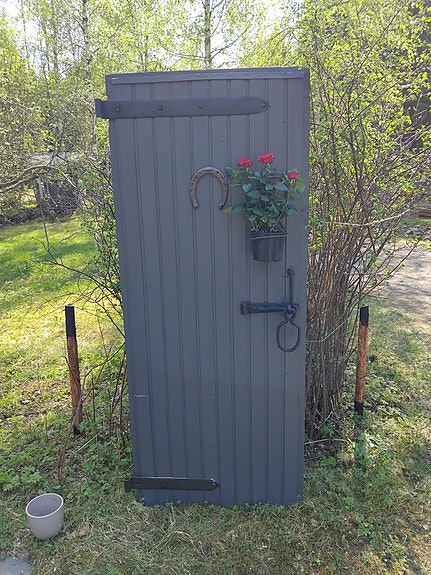Puinen harmaa ulko-ovi takorautaheloilla