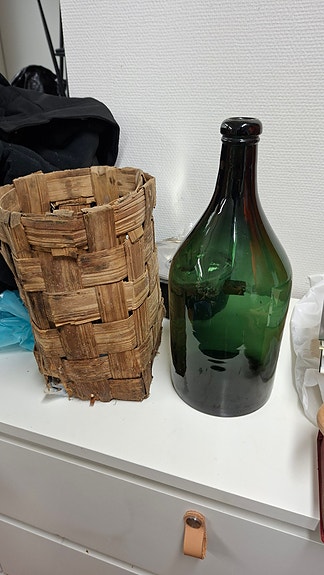 Vihreä lasipullo ja pärekori