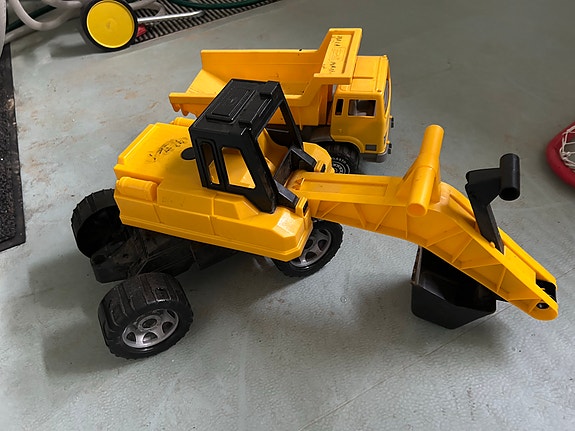 Keltainen leikkikaivuri ja Plasto kuorma-auto