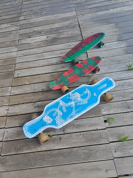 Longboard ja kaksi muovista cruiser-lautaa