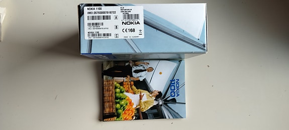 Nokia 1100 puhelimen myyntipakkaus ja käyttöohjeet