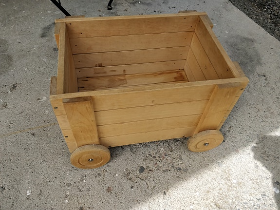 Täyspuinen pyörillä oleva lelulaatikko.