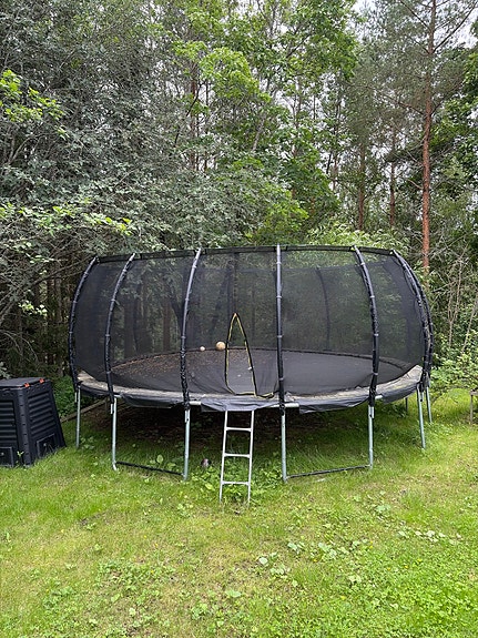 Iso trampoliini turvaverkolla ja tikkaille