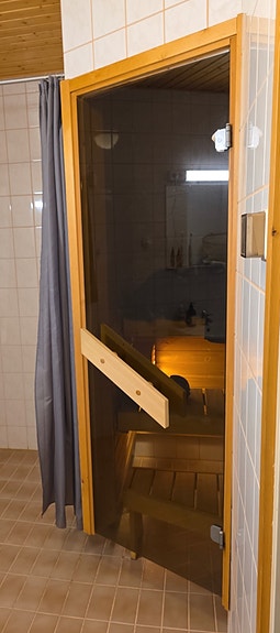 Lasinen saunanovi karmilla