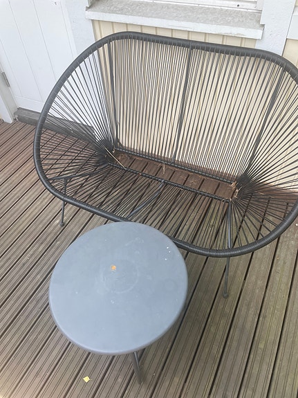 Musta terassisohva ja pyöreä pöytä ulkokäyttöön