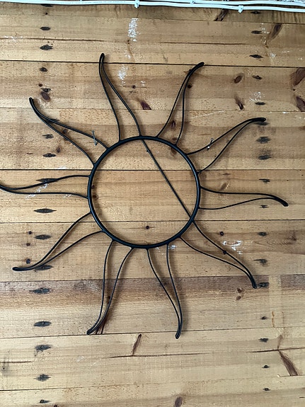 Metallinen musta aurinko seinälle.