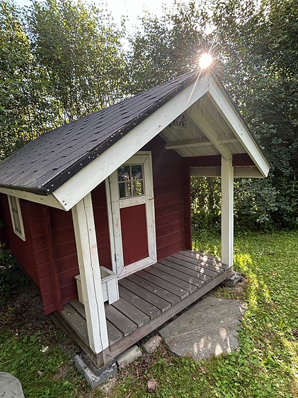 Punainen leikkimökki terassilla