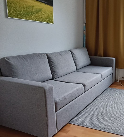 Harmaa kolmen istuttava sohva