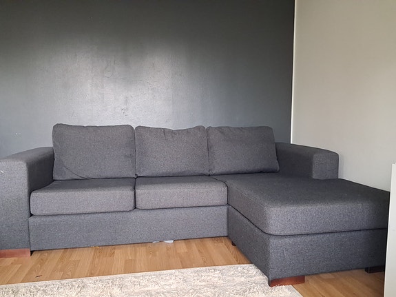 Tummanharmaa 3 istuttava sohva divaanilla