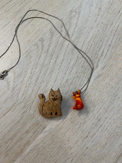 Hopeinen kissa kaulakoru ja puinen kissa pinssi