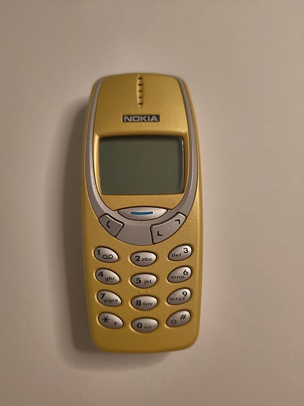 Nokia 3310 keltaisilla kuorilla ja laturilla sekä uudella akulla