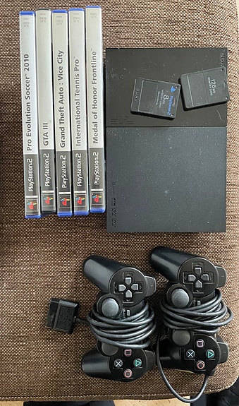 Sony PlayStation 2 konsoli ohjaimilla ja peleillä