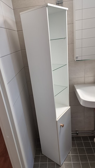 Valkoinen kylpyhuoneen korkea kaappi lasihyllyillä